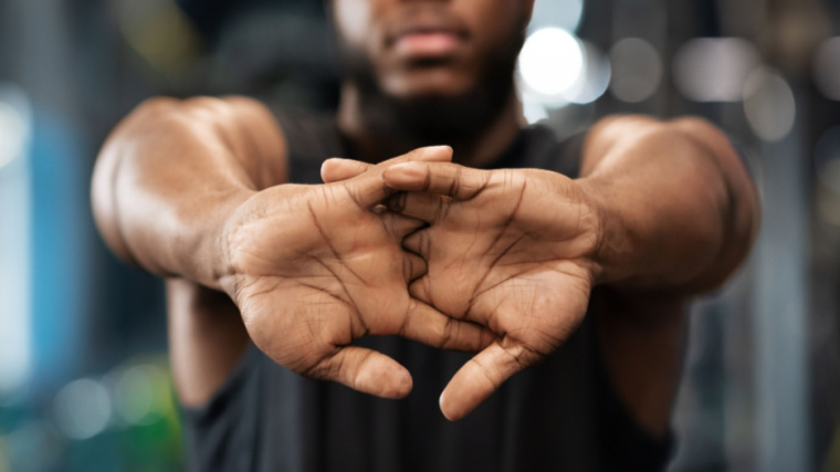 A close-up image shows a person extending their interlocked fingers in a stretch toward the camera.