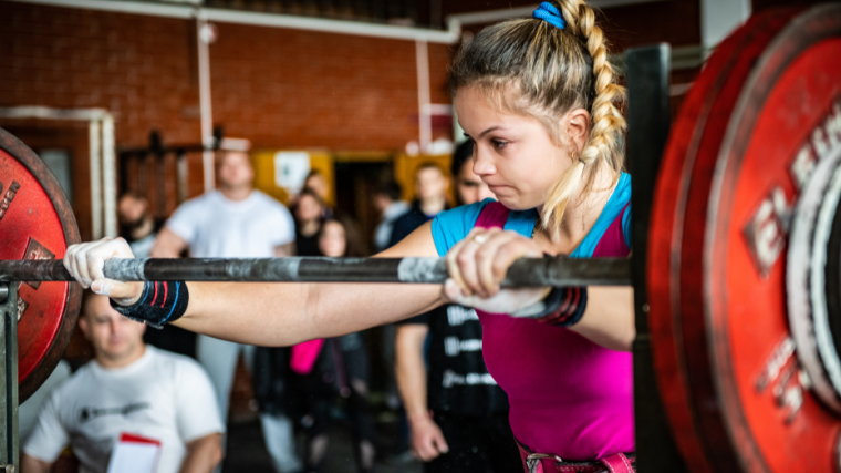 Little girl sets up to back squat at powerlifting competition