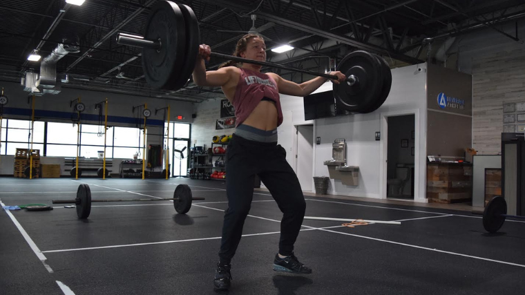 weightlifter descends to catch barbell overhead in snatch