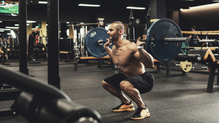 Man performs standard back squat in gym