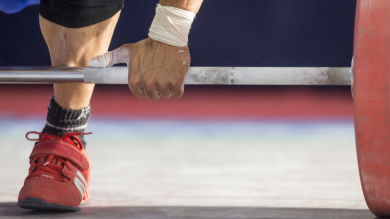 weightlifter grabs bar at competition