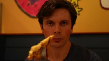 A person holding French toast on a fork up to the camera.