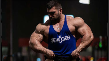 A bodybuilder posing in a blue tank top.