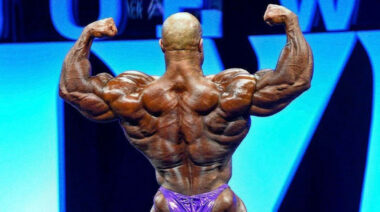 Bodybuilder Phil Heath posing from behind on stage.