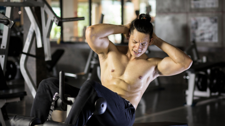 A shirtless person performs decline crunches.