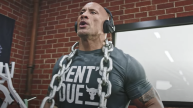 Actor Dwayne Johnson in the gym with chains around his neck.