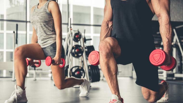 pair of gymgoers perform lunges in sync