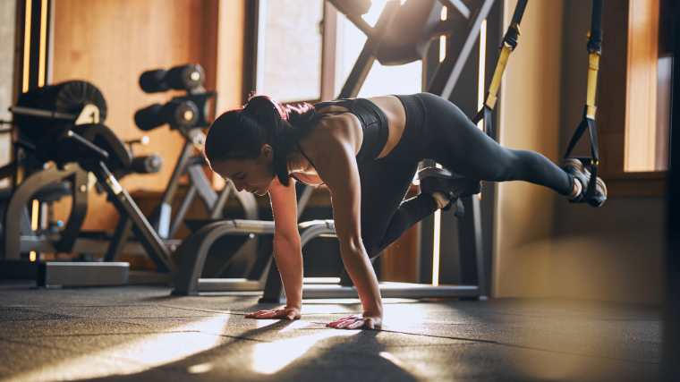 woman performs bodyweight ab workout in sunny gym