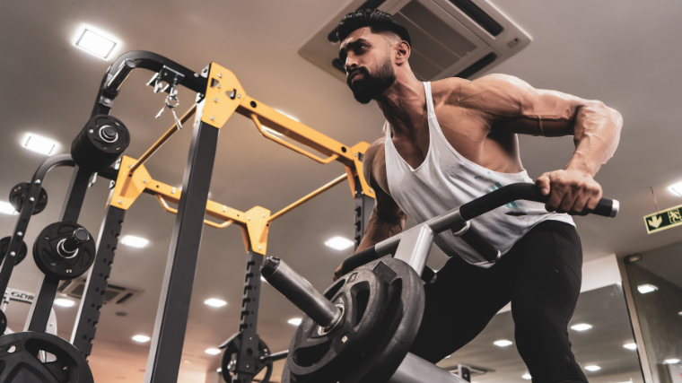 Men in stringer tanks perform sets of T-bar columns with wide grips.