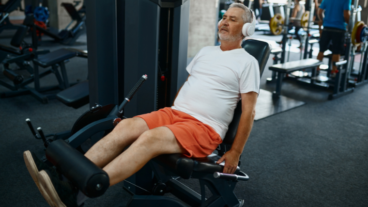 elderly man performs workout on leg extension machine