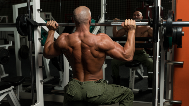 man peforms seated shoulder press on smith machine