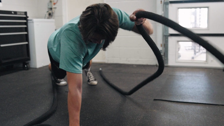 slim athletic woman working out with battle rope in gym. fitness