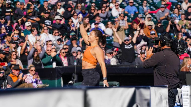 CrossFitter Laura Horvath raising her hand in front of a crowd at the 2022 Rogue Invitational.