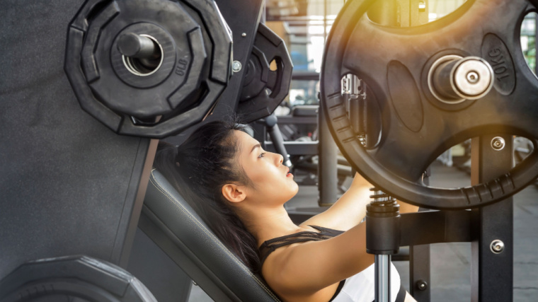 An athlete performs an incline press with weight plates on a machine.