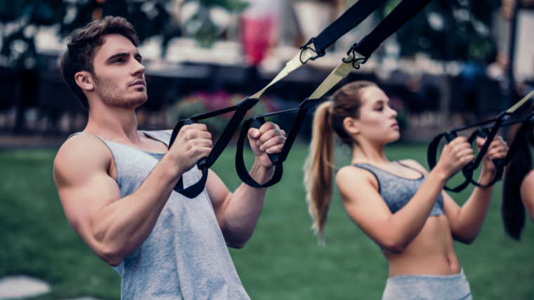 couple of athletes working out outdoors using TRX cables