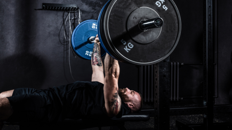 athlete performs bench press in gym