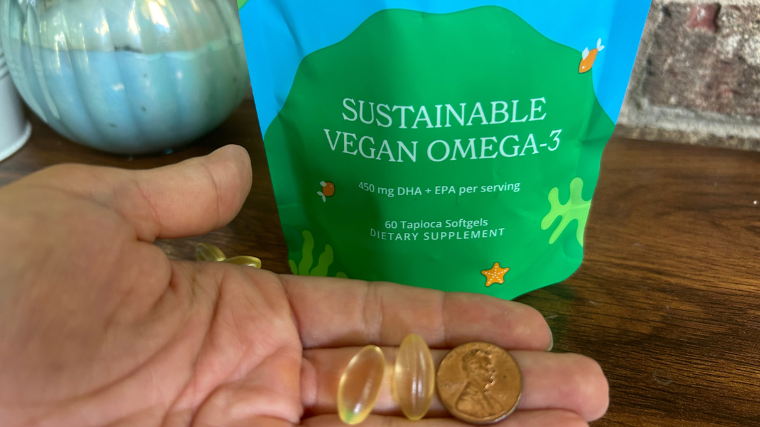 A person demonstrates that Calgee Vegan Omega-3 capsules are about the size of a penny.