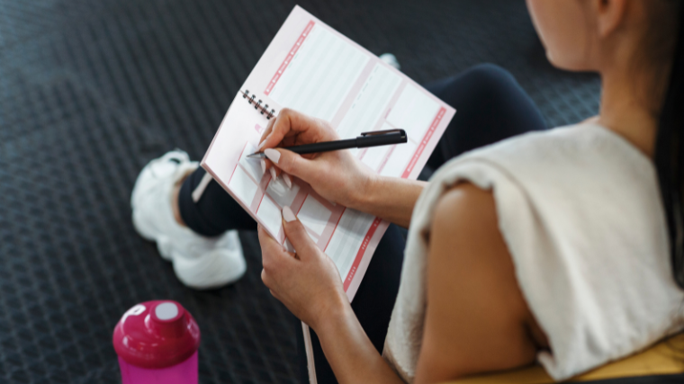 Athlete planning workout and nutrtion goals on paper in gym