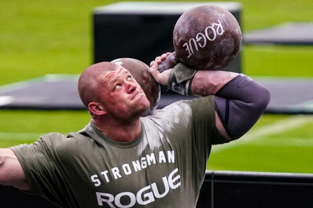 Strongman Pavlo Nakonechnyy shoulders a 280-pound metal Cyr dumbbell before pressing it overhead.
