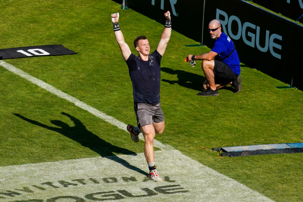 CrossFit athlete raises his hands after finishing an event.