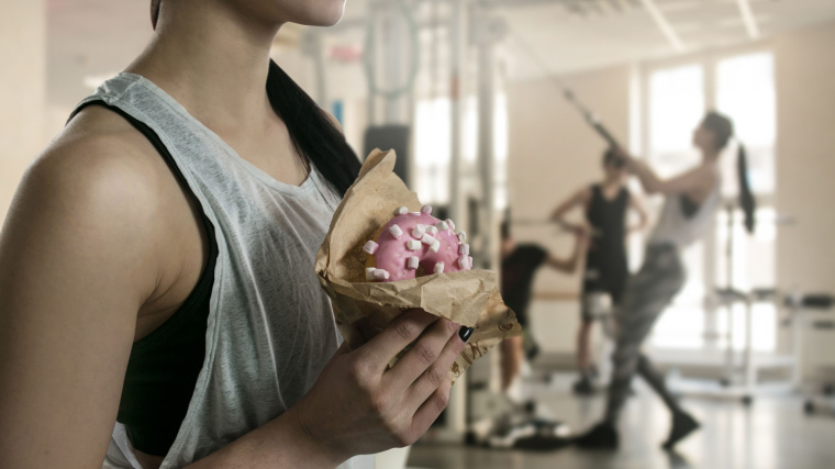 A person holds a donut in the gym.