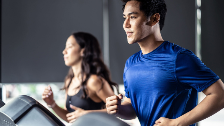 Two people run on adjacent treadmills.