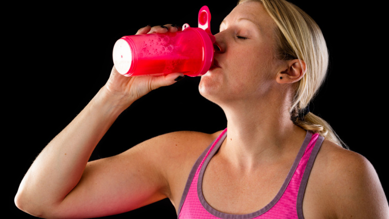 Woman in pink top drinking from a shaker bottle
