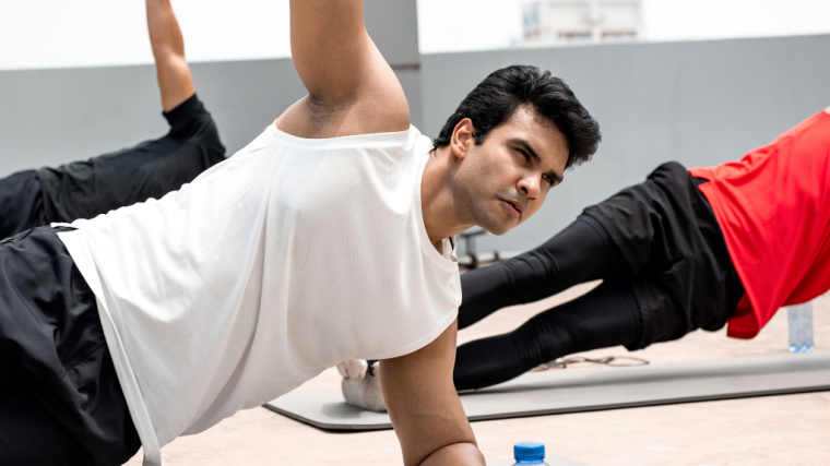 A few people perform a side plank in a group fitness class.