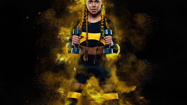 A person with braids stands with dumbbells in their hands with yellow mist surrounding them.