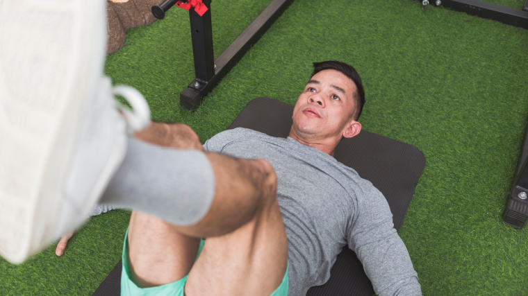 A person performs an ab exercise on turf in the gym.