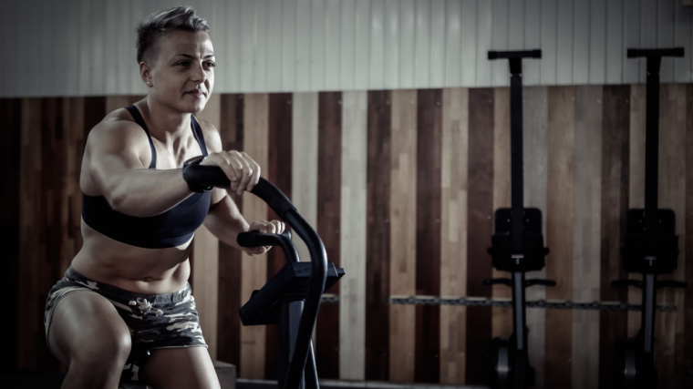 A person exercises on an air bike in the gym.