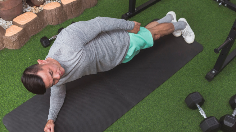 A person performs a side plank in the gym.
