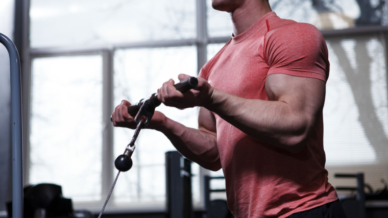 A person performs cable curls in the gym.