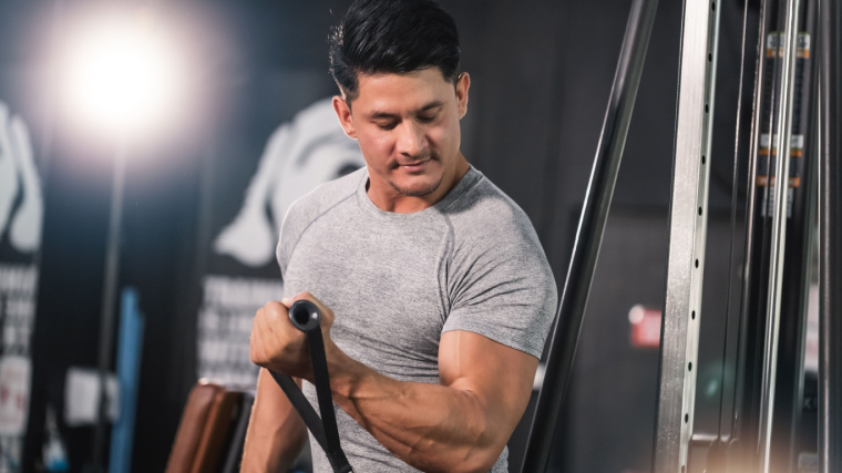 A person performs a single-arm cable curl in the gym.