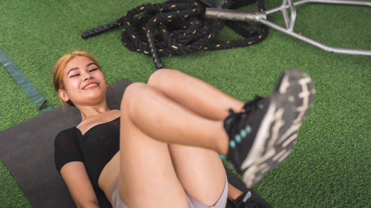 A person performs a reverse crunch on turf in a gym.