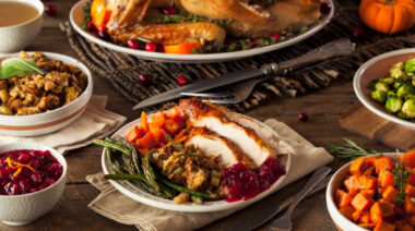 A full table is loaded with Thanksgiving dishes.