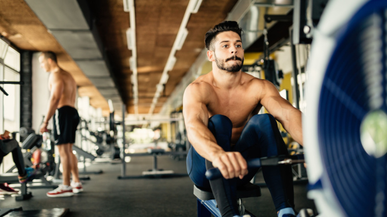 A person rows on a rowing machine in the gym.