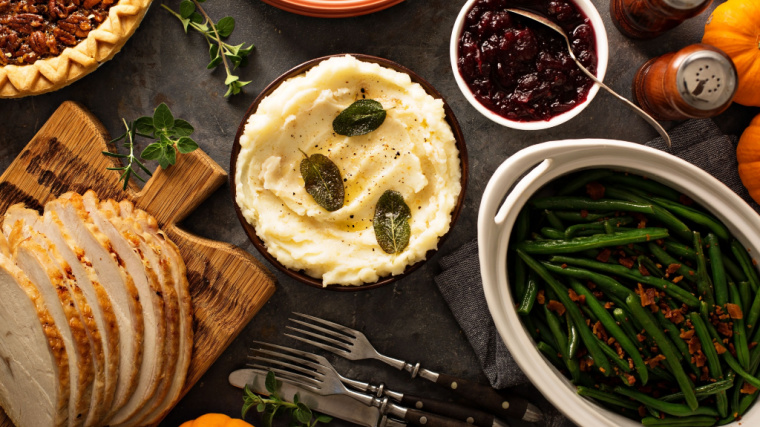 A table is full of Thanksgiving plates, including green beans, mashed potatoes, and cranberry sauce.