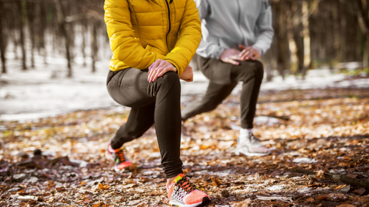 Pair of exercisers perform lunges outdoors in wintry setting