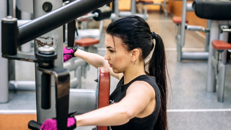 woman performs reverse pec deck while wearing lifting gloves