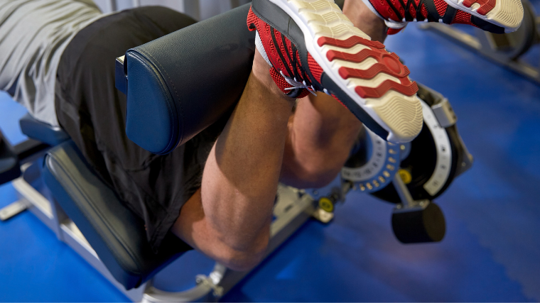 athlete performing leg curls on machine in gym