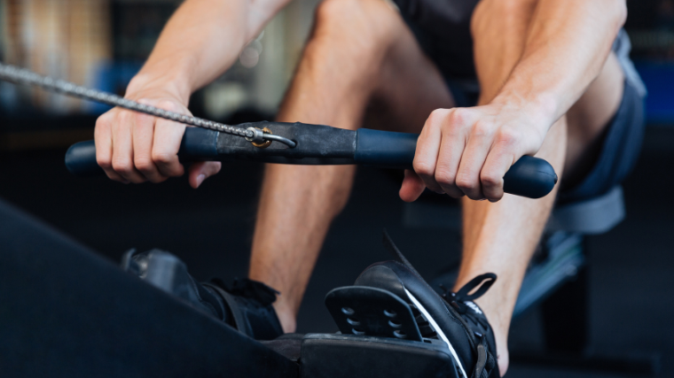 Athlete grabbing onto rowing machine handle before performing a row.