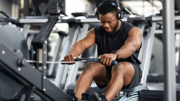 Athlete focusing on rowing form while atop rowing machine.