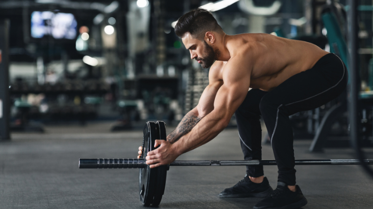 Athlete putting on plates into barbell preparing for next set