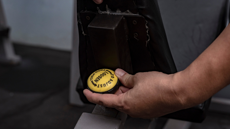 Person adjusting machine seat in the gym