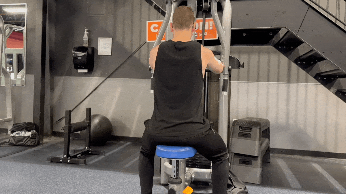 A GIF of a person performing reverse flyes on a peck deck machine.