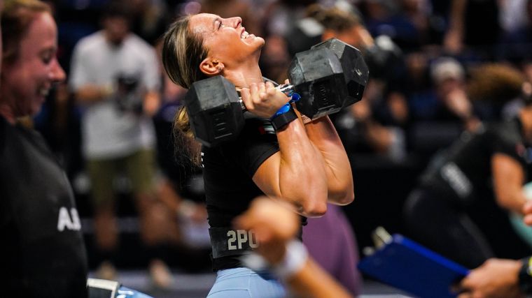 CrossFitter holding two dumbbells on their shoulders, getting ready to press them overhead.