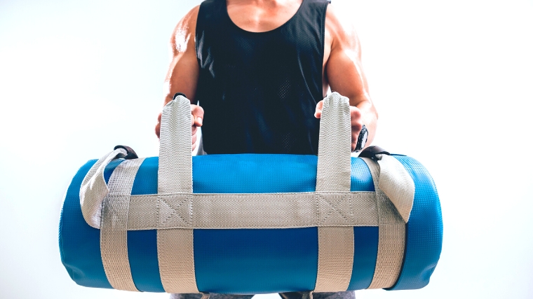 Athlete training with a sandbag in the gym.