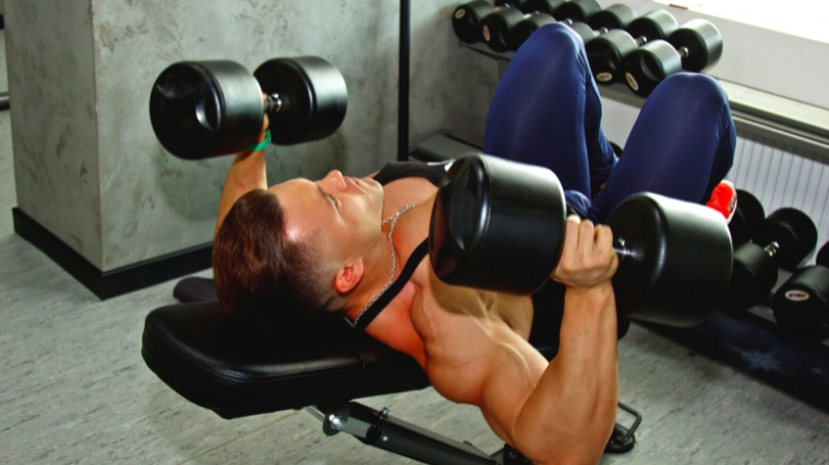 Engaged muscles as a person exercises with dumbbells