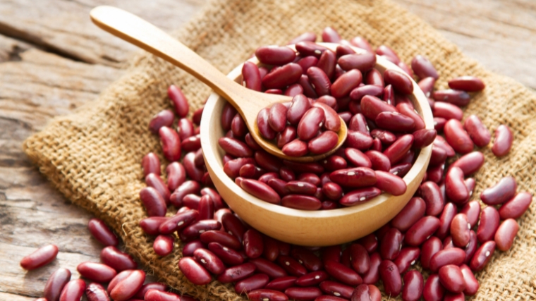 Kidney beans in a wooden bowl with a wooden spoon.